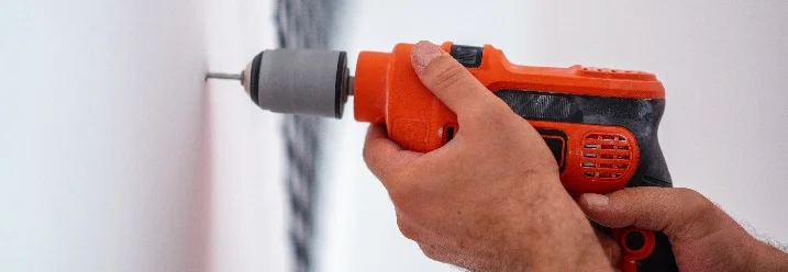 Person bohrt mit Bohrmaschine in Wand