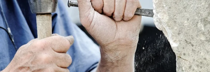 Person meißelt Stein