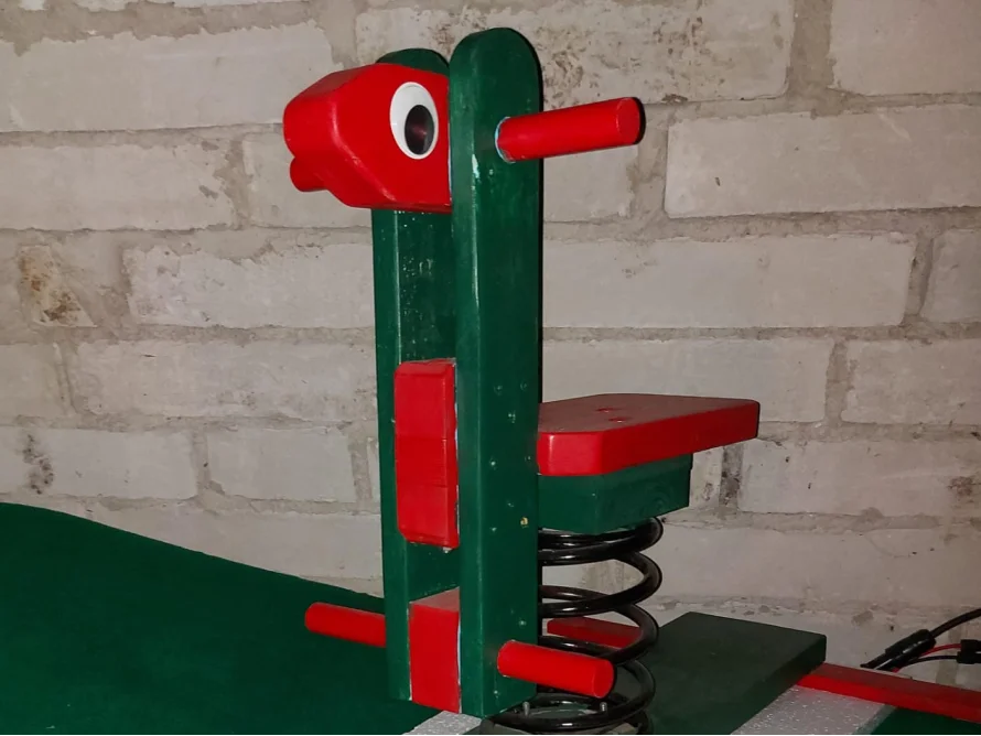 grünes Spielzeugpferd mit rotem Kopf und Sitz