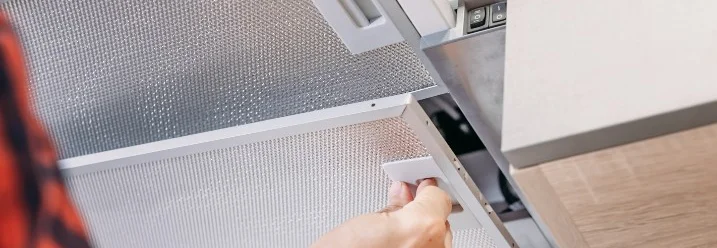 Hand setzt Filter in Dunstabzugshaube ein