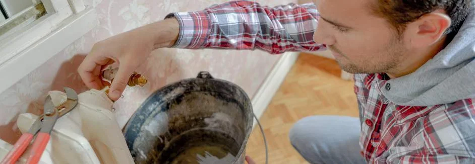 Person repariert Heizkörper mit Zange