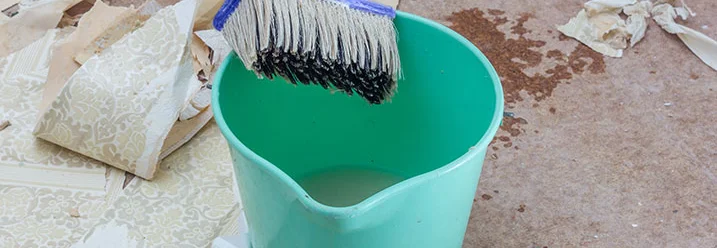 Eimer, Tapezierbürste und Tapetenreste