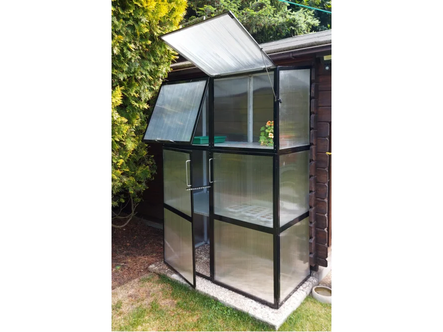 Kleines Gewächshaus mit durchsichtigen Wänden und geöffnetem Dach