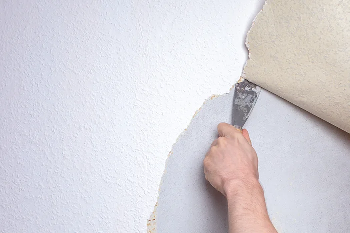 Hand entfernt Tapete mit Spachtel