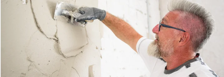 Person verputzt Wand mit Kelle