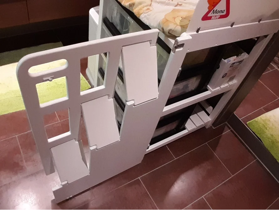 Ein weißes Babybett mit einer offenen Klappe.