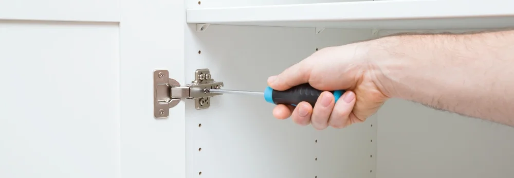 Hand justiert Möbelscharnier mit Schraubendreher