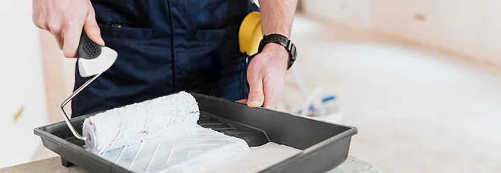 Person trägt Farbe mit Farbroller auf