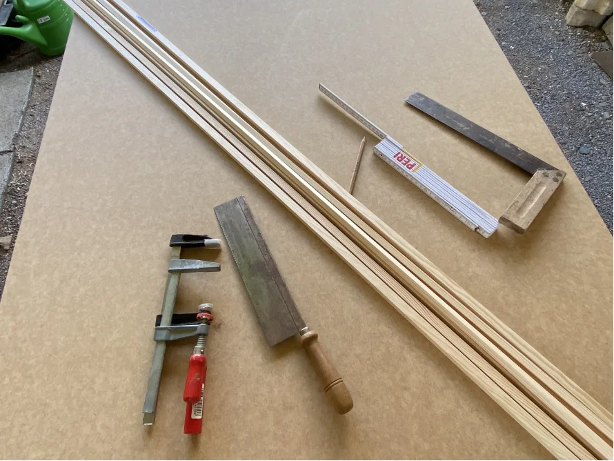 Holzlatten, Säge und Winkel auf einer Holzplatte