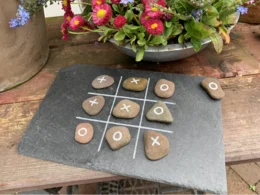 Tic-Tac-Toe Spiel mit Steinen auf Schiefertafel