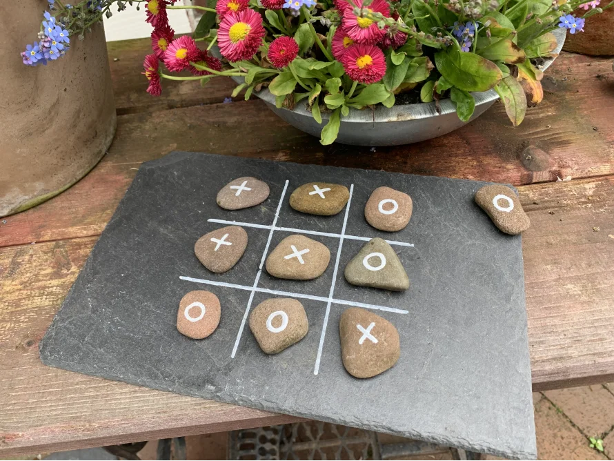 Tic-Tac-Toe Spiel mit Steinen auf Schiefertafel