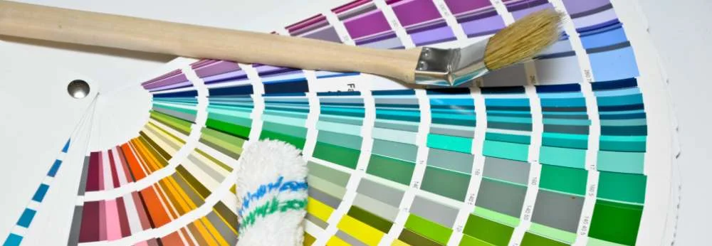 Ein Farbfächer mit einem Pinsel und einer Farbrolle.