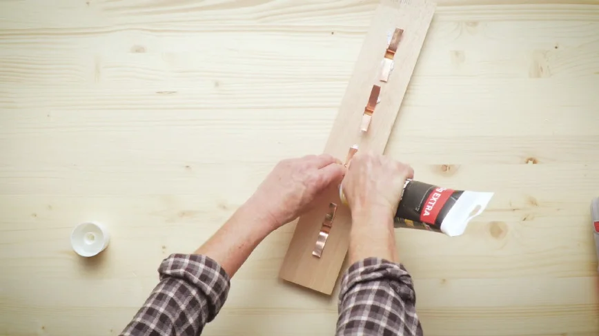 Person bringt Klebstoff auf Holzbrett an