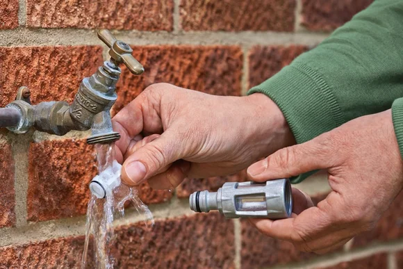 Person bringt Wasserfilter an Wasserhahn an