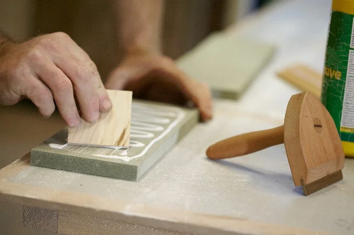 Person trägt Leim mit Spachtel auf