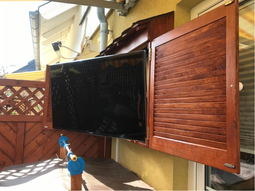 Fernseher in Holzverschlag auf Terrasse