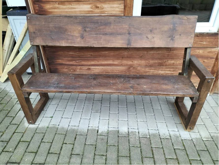 Rustikale Holzbank auf einem gepflasterten Weg