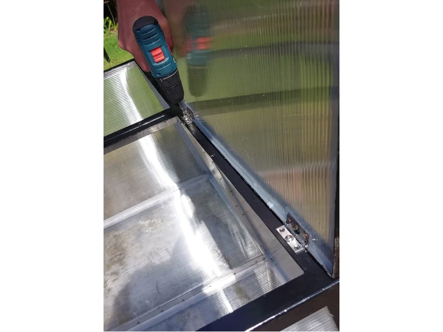 Person befestigt Gewächshaustür mit Akkuschrauber