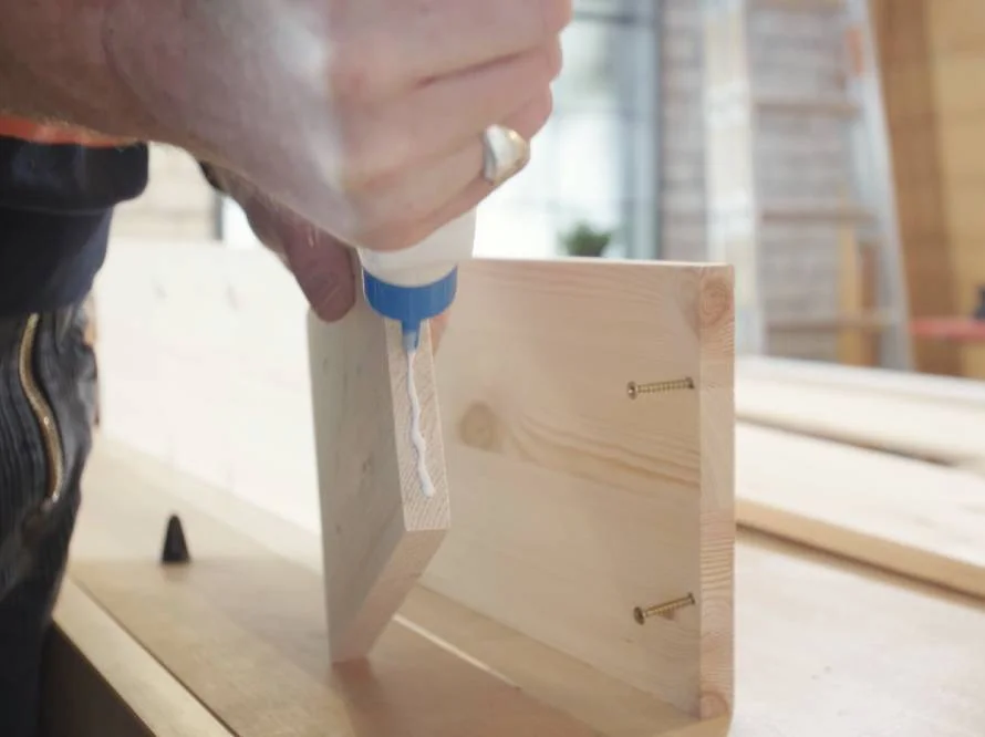 Person klebt Holzbrett mit Klebstoff