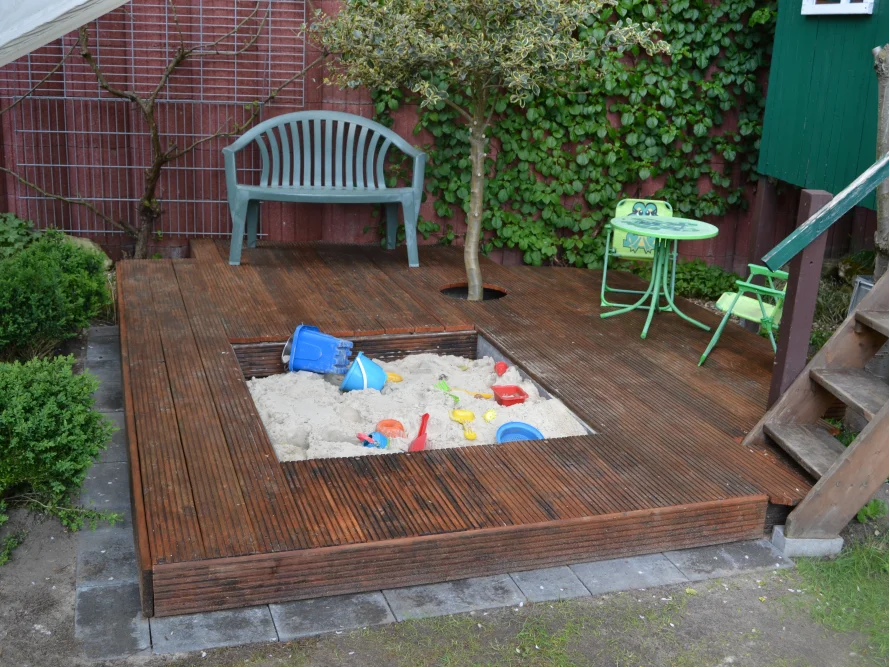 Sandkasten auf Holzterrasse mit Spielzeug
