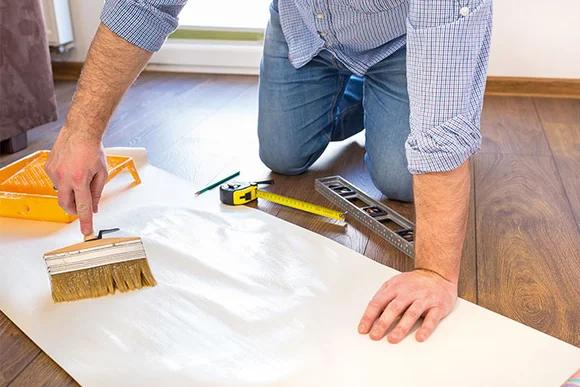 Person trägt Kleister auf Tapete auf