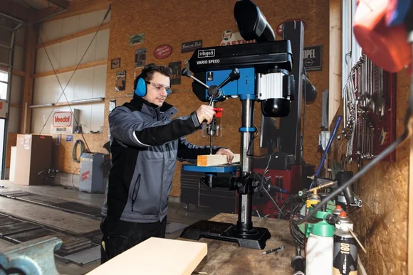 Person bohrt mit Standbohrmaschine