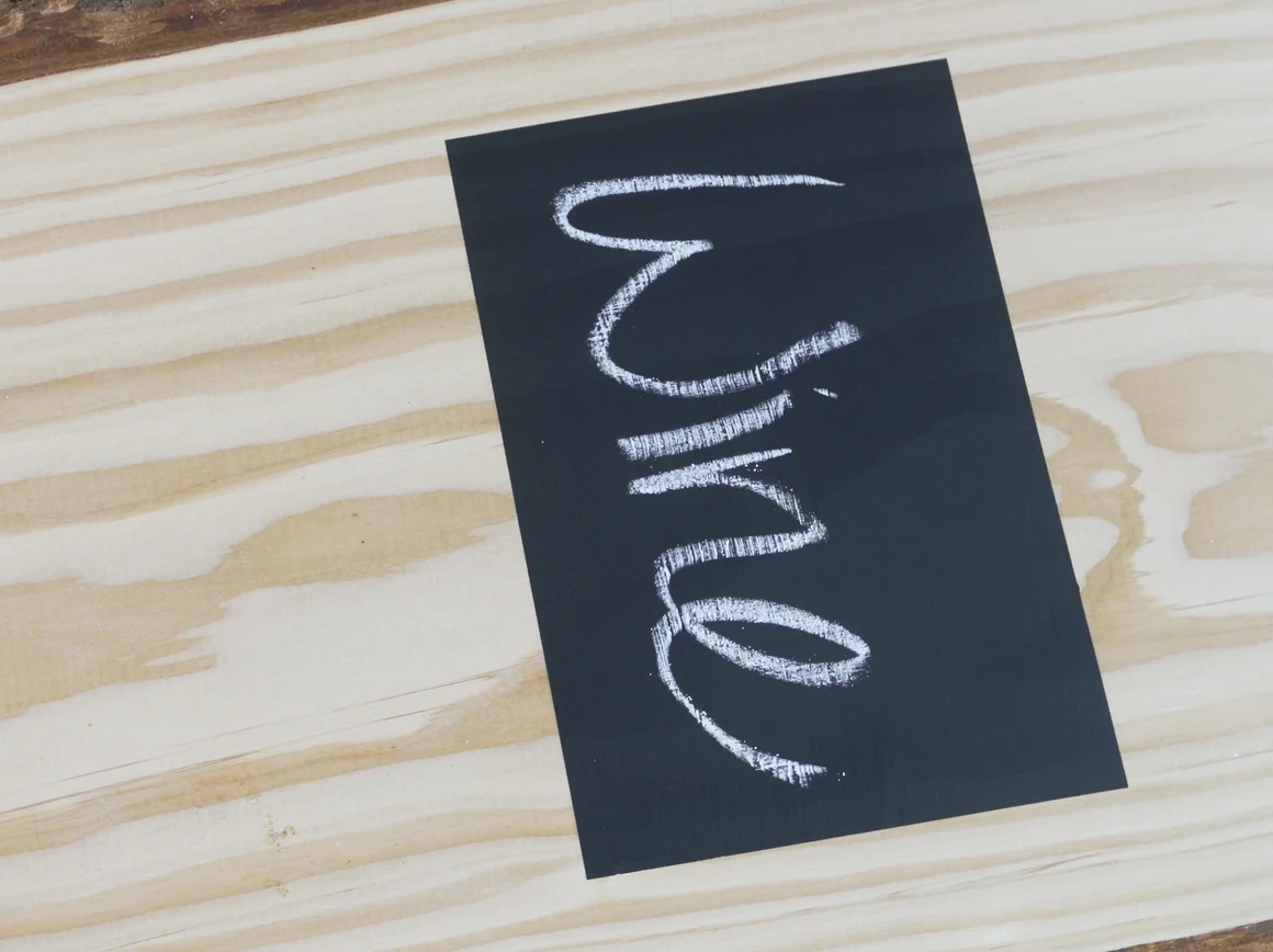 Schwarzes Etikett mit Kreideschrift auf Holz