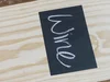 Schwarzes Etikett mit Kreideschrift auf Holz