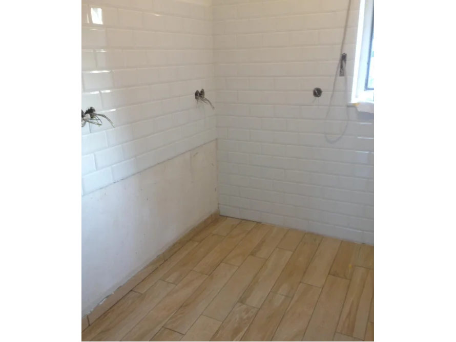 Badezimmer mit weißen Fliesen und hellem Holzboden