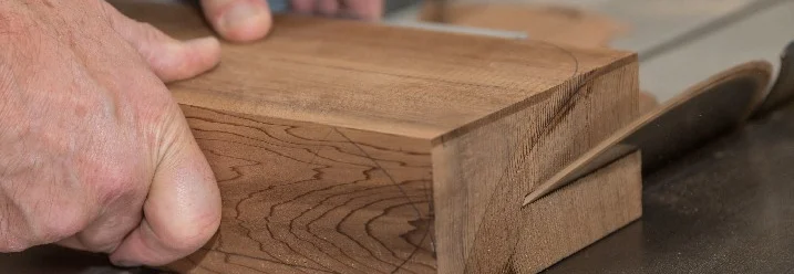 Hände führen Holz an Kreissäge