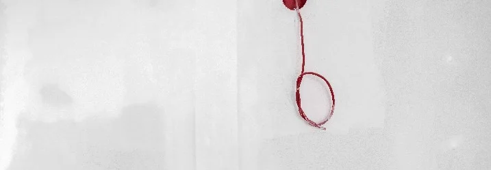 Rotes Kabel aus Loch in Wand
