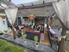 Eine gemütlich eingerichtete Terrasse mit vielen Pflanzen und Sitzmöbeln.