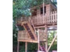 Ein Baumhaus aus Holz mit Zaun und Treppe.