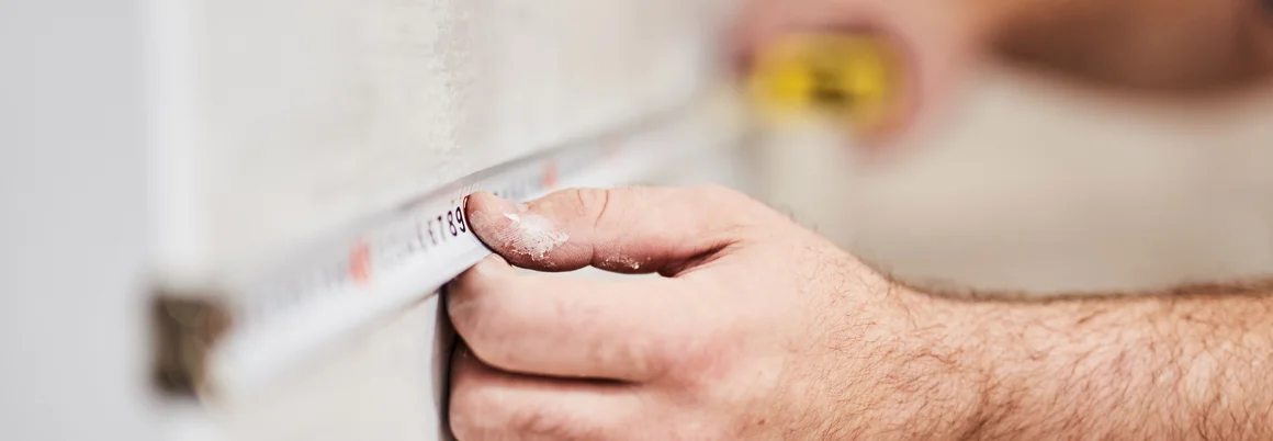 Person misst Wand mit Zollstock