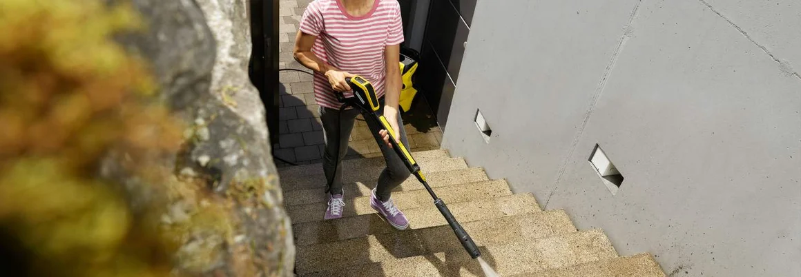Person reinigt Steintreppe mit Hochdruckreiniger
