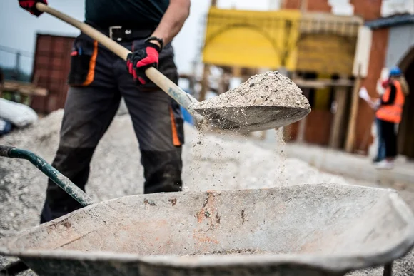 Person schaufelt Kies in Schubkarre