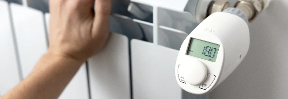 Person stellt Temperatur an Heizung ein