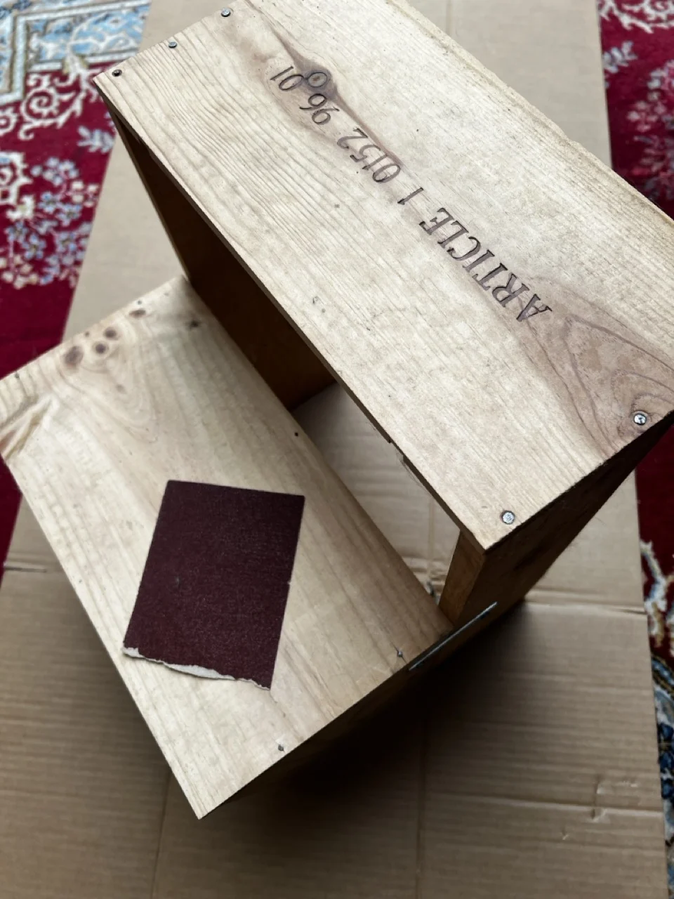 Eine Holzkiste wird mit Schleifpapier abgeschliffen.