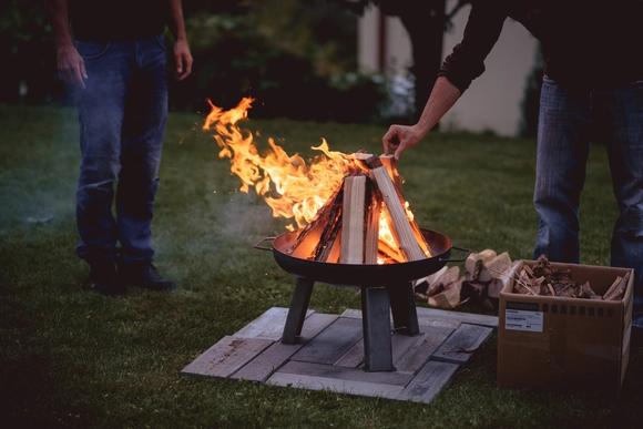 Zwei Personen an einer brennenden Feuerschale im Garten.