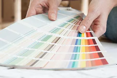 Person wählt Farbe aus Farbmusterkarte