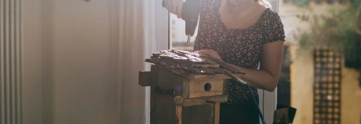 Person baut mit Akkuschrauber ein Vogelhaus