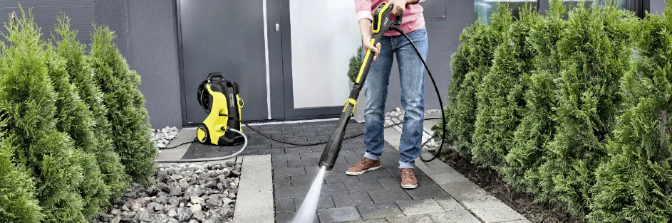 Person reinigt Pflaster mit Hochdruckreiniger