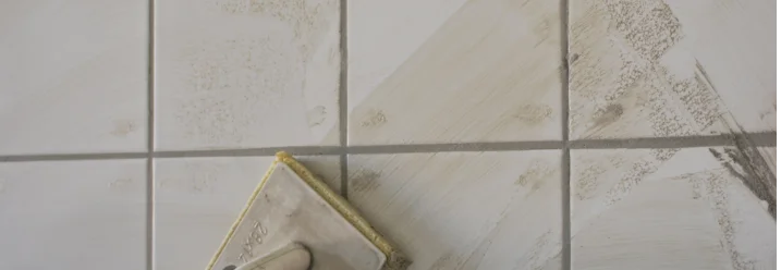 Hand mit Schwamm verfugt Fliesen