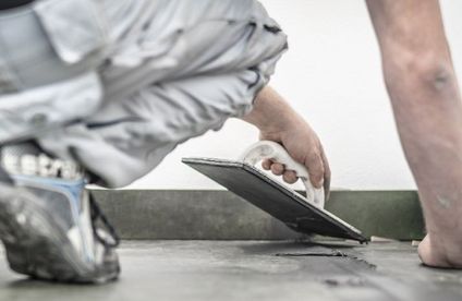 Natursteinfliesen verfugen Handwerker verfugt Naturfliesen auf dem Boden.