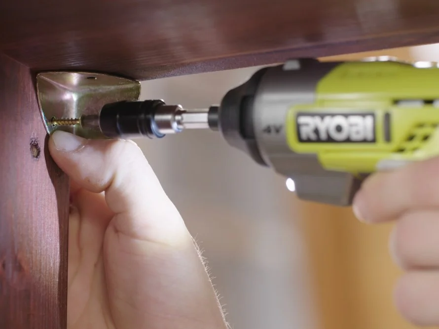 Person schraubt Winkel an Holz