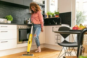 Person reinigt Boden mit Dampfreiniger