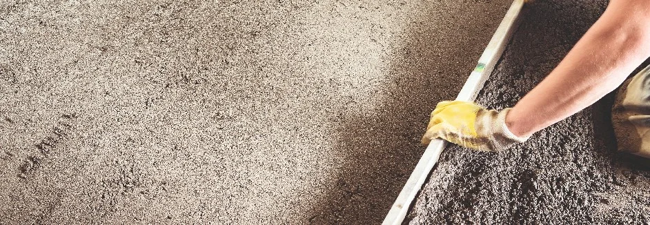 Person ebnet Betonboden mit Richtlatte