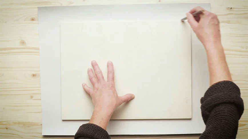 Person zeichnet auf Holzplatte