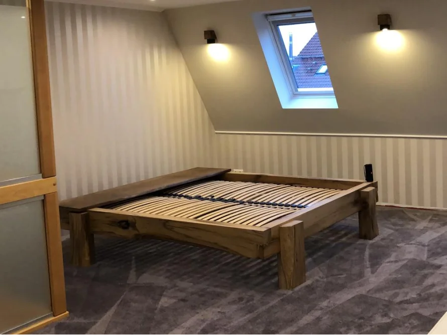 Holzbett in einem Schlafzimmer mit Dachfenster