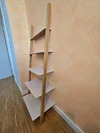Ein leeres Anlehnregal aus Holz mit weißen Böden.
